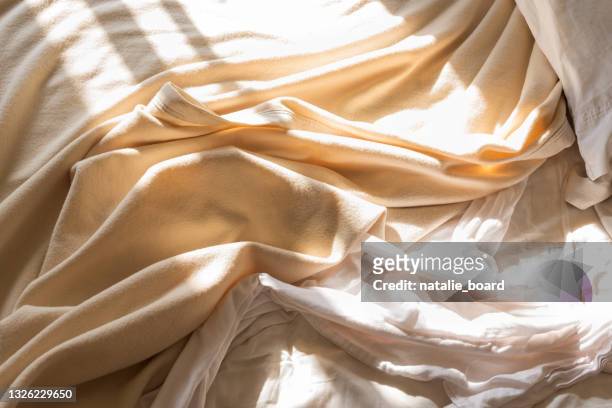 close up of messy bed sheet and blanket in morning sunlight - bedding stock pictures, royalty-free photos & images