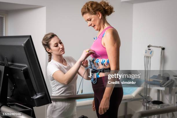 女性の胸に電極を置く女性医師 - stress test ストックフォトと画像