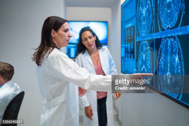 female radiologists looking at the mri images on the lightbox - neuroscience stock pictures, royalty-free photos & images