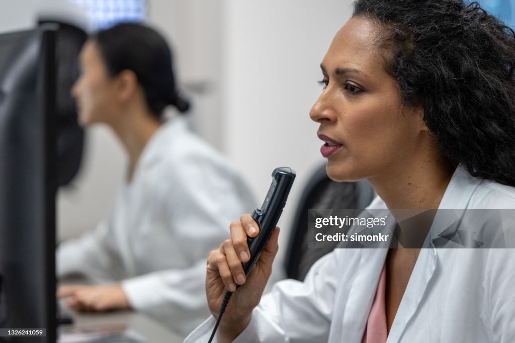 Female Radiologist Speaking Into A Dictation Recorder While Looking At ...