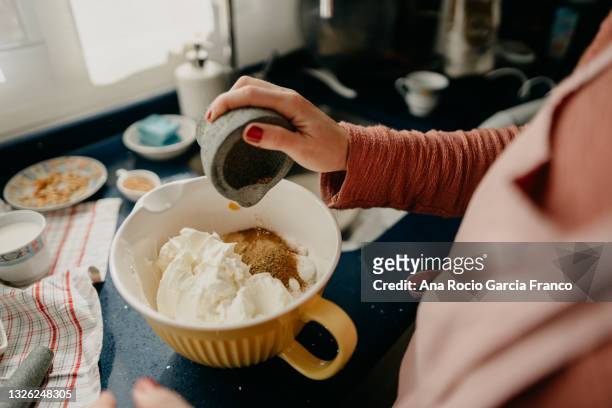 woman chef pours species for the pumpkin cheesecake dough into a bowl - cucinare un dolce foto e immagini stock