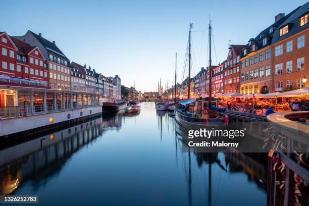 colorful houses along the canal at nyhavn at night. copenhagen, denmark. - copenhagen stock-fotos und bilder