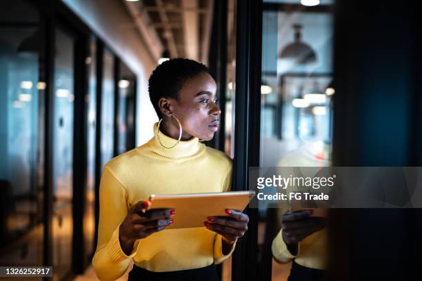 young business woman using digital tablet and looking away in an office - forecasting stockfoto's en -beelden
