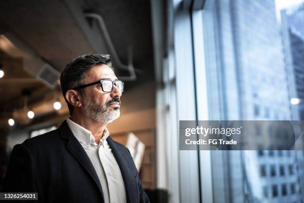 hombre de negocios maduro mirando por la ventana - future fotografías e imágenes de stock