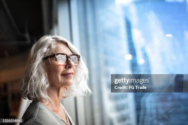 mature businesswoman looking out of window. - imagination vision stockfoto's en -beelden