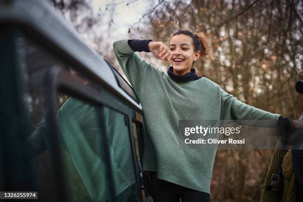 laughing teenage girl with father at a car in forest - 12 13 girl stock-fotos und bilder