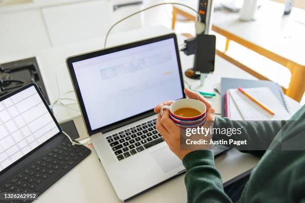 a working from home setup on the kitchen worktop. a man takes a break with a cup of tea - 40's rumpled business man stockfoto's en -beelden