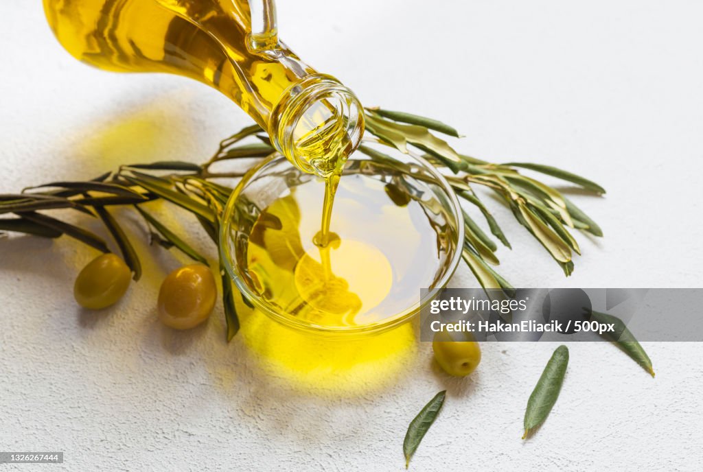 High angle view of olive oil pouring in bowl on table
