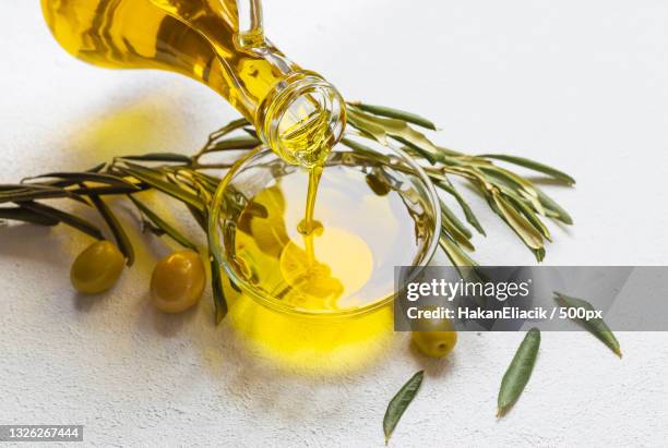 high angle view of olive oil pouring in bowl on table - olive fotografías e imágenes de stock