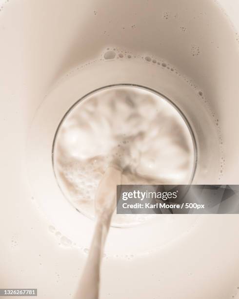 cropped image of milk being poured into a glass on white background - milk pour white background bildbanksfoton och bilder