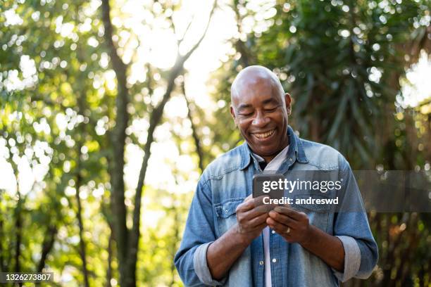 middle-aged man smiling and using cell phone. - man texting stockfoto's en -beelden