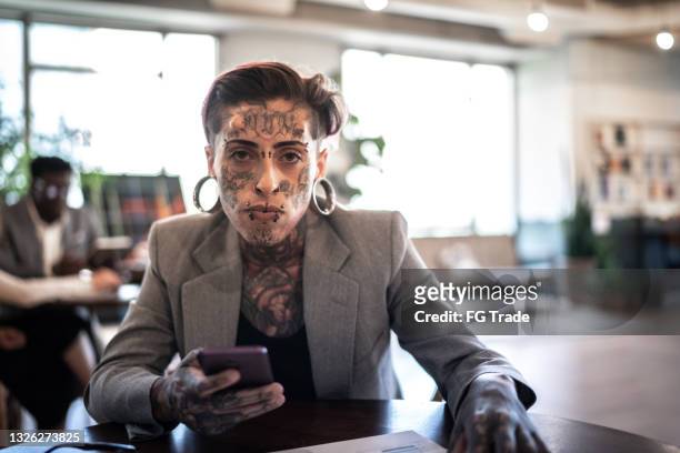 portrait of tattooed businesswoman using smartphone at work - portrait of cool creative businesswoman at office bildbanksfoton och bilder