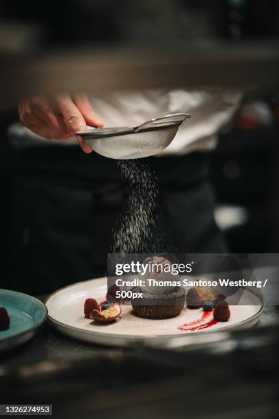 midsection of chef sprinkling powered sugar in plate on table,sverige,sweden - toetje stockfoto's en -beelden