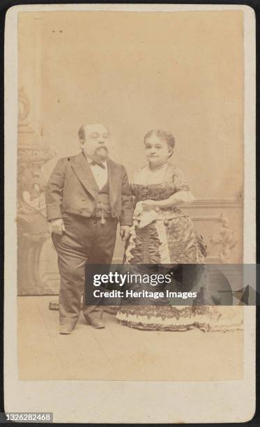 Carte-de-visite of Tom Thumb and Lavinia Warren shown in full portrait. Both are standing and facing slightly toward each other looking off frame....