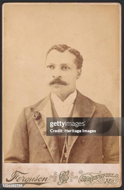 Black and white photograph of Tobe Brown.;Brown is pictured from the waist up. He has curly hair with a side part and a long mustache. He is wearing...