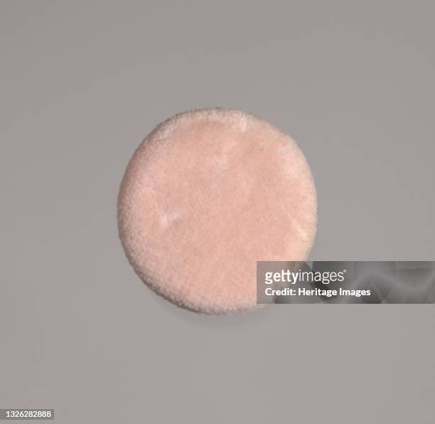 Pink circular powder puff made from two layers of faux fur filled with soft foam and found in 2010.6.54.1ab. Mae Reeves was a pioneering...
