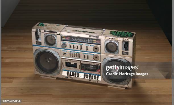 Tecsonic boombox with a light brown metal cover used by Public Enemy. The boombox has a handle at the top, collapsible antenna, six speakers, a...