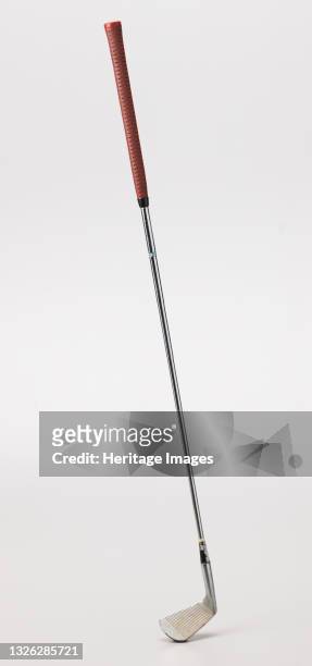 Iron golf club used by African-American golfer Ethel Funches.;The shaft is silver in color and is made out of metal. There is a red rubber grip at...