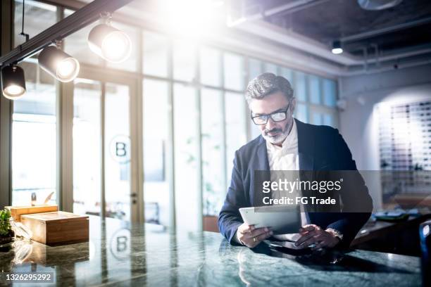 mid adult man working using digital tablet - chief executive officer stock pictures, royalty-free photos & images