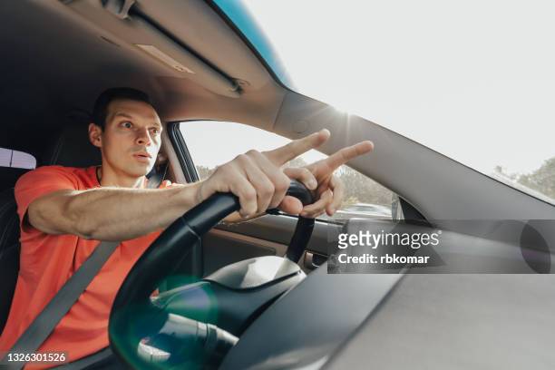shocked young man driver gesturing driving a car - mann erschrocken stock-fotos und bilder