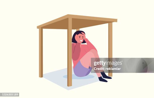 the young woman was afraid of the earthquake, she hid under the table to protect herself. worried scared woman vector. an illustration of an example showing the behavior to be done in the event of an earthquake. - earthquake stock illustrations