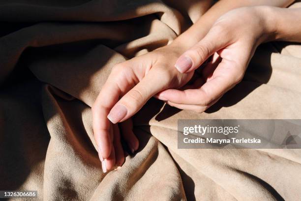 beautiful female hands with gentle manicure on a fabric background. - uñas fotografías e imágenes de stock