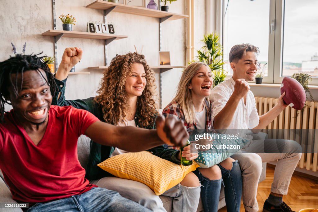 Excited fans cheering for sport team watching American football game