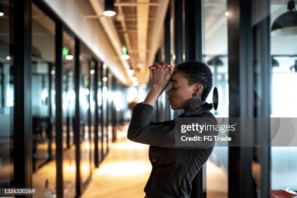 worried young business woman at corridor office - physical pressure stockfoto's en -beelden