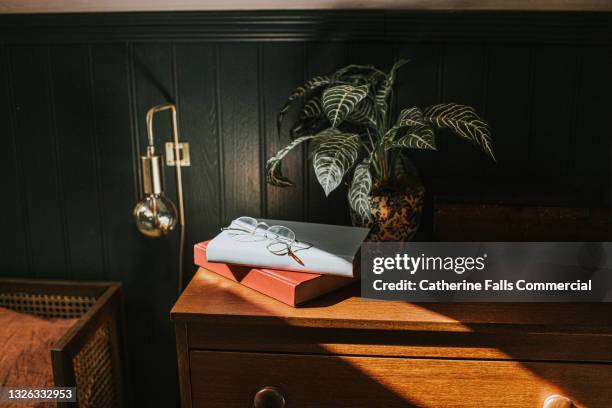 reading glasses on two books stacked on a bedside table - book on table foto e immagini stock
