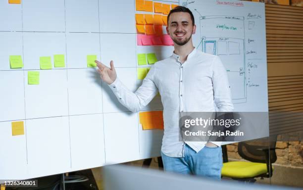 employee is standing in front of white board with sticky notes on it. - sticky stock pictures, royalty-free photos & images