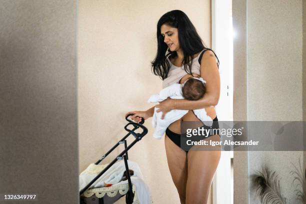 mother carrying baby and pushing stroller - kids in undies stockfoto's en -beelden