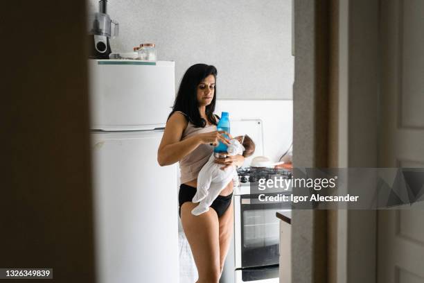 breastfeeding and holding a bottle of water - dia bildbanksfoton och bilder