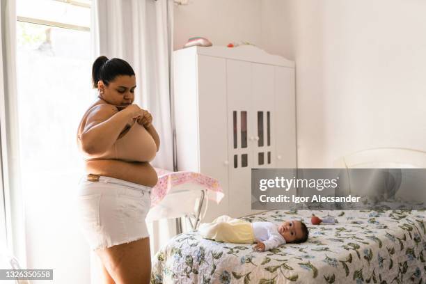 mother closing a breast-feeding bra - chubby belly girl stock pictures, royalty-free photos & images