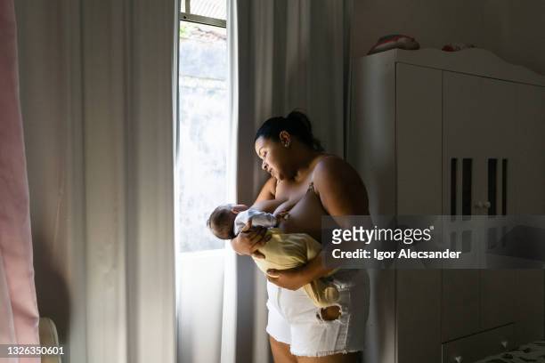 madre amamantando en la ventana - girls in bras photos fotografías e imágenes de stock