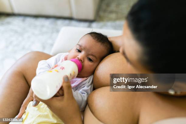 mutter, die dem baby eine flasche gibt - große brüste stock-fotos und bilder