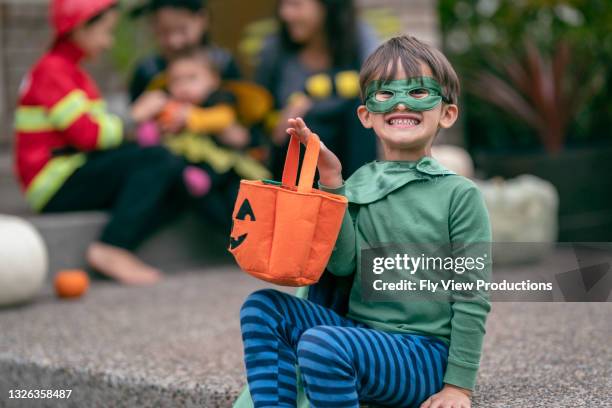 excited little boy holding bag of halloween candy - boy fireman costume stock pictures, royalty-free photos & images