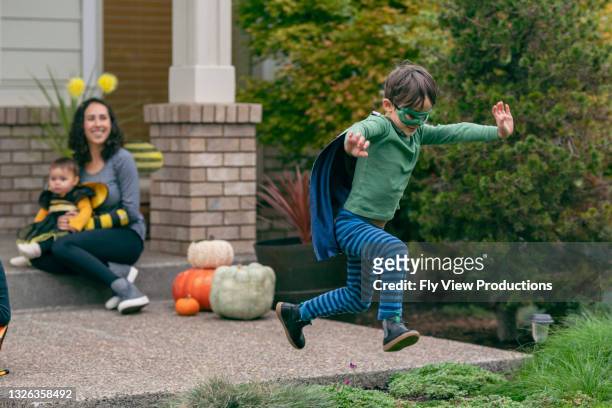 boy in superhero costume jumping for joy on halloween - baby superhero stock pictures, royalty-free photos & images