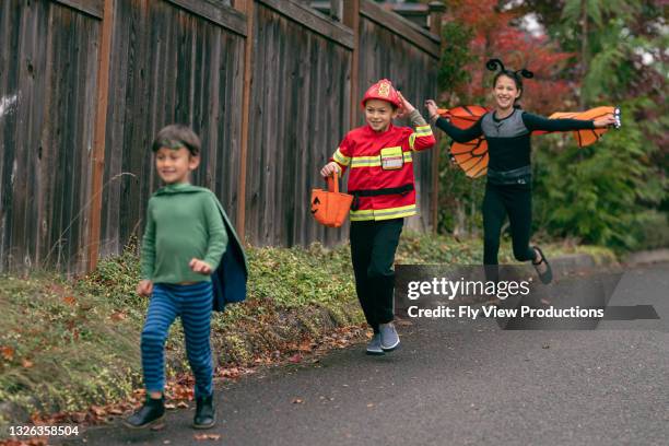children running along street while trick or treating - halloween covid stock pictures, royalty-free photos & images