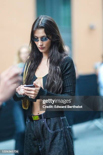 Bella Hadid wears a black ribbed opened cardigan, a yellow fluffy bag, a Fendi belt, during Jacquemus "La Montagne" Show, at La Cite Du Cinema on...