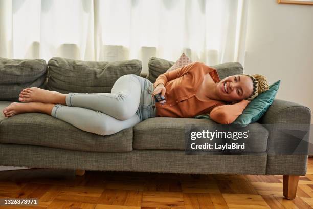 shot of a young woman watching tv on the sofa at home - binge watching stock pictures, royalty-free photos & images