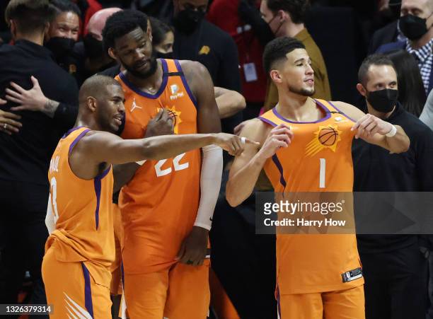 Devin Booker of the Phoenix Suns celebrates with teammates Deandre Ayton and Chris Paul following the team's series win against the LA Clippers in...
