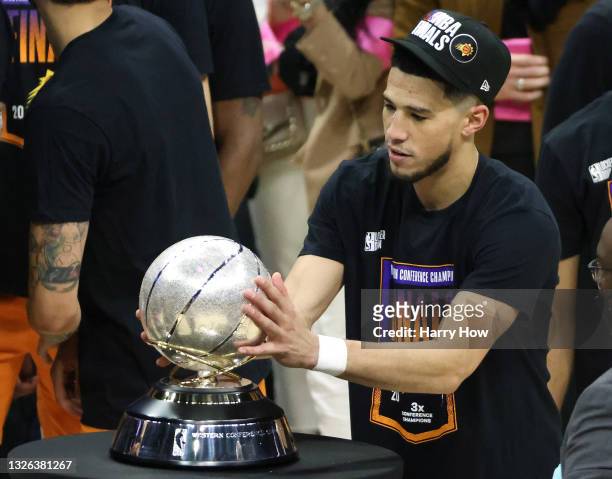 Devin Booker of the Phoenix Suns holds the Western Conference Championship trophy after the Suns defeated the LA Clippers in Game Six of the Western...