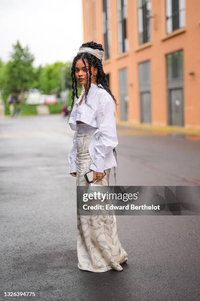 Sharon Alexie @flammedepigalle wears a white cropped shirt with long flared sleeves, high waist white flared pants with pale blue floral print, a...