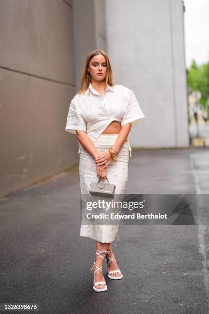 Angelina Woreth wears a white cropped shirt with short wide sleeves, a high-waist midi skirt with attached sticks depicting branches, a gray suede...