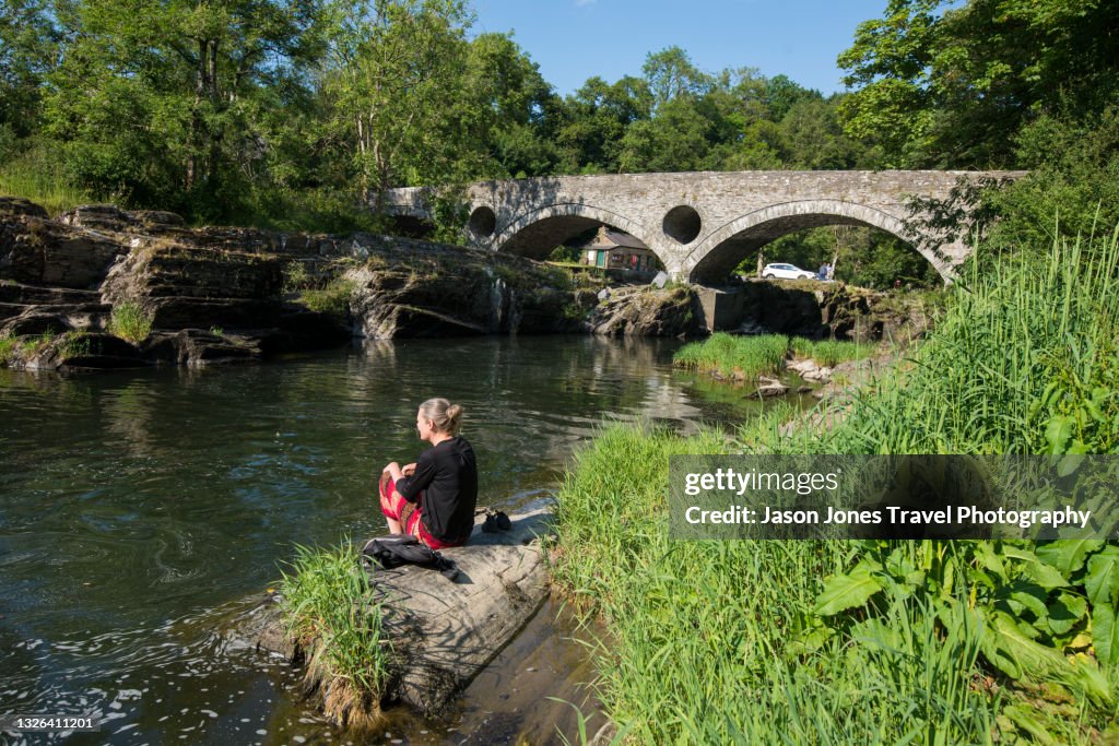 Person sitting on the bank of a river