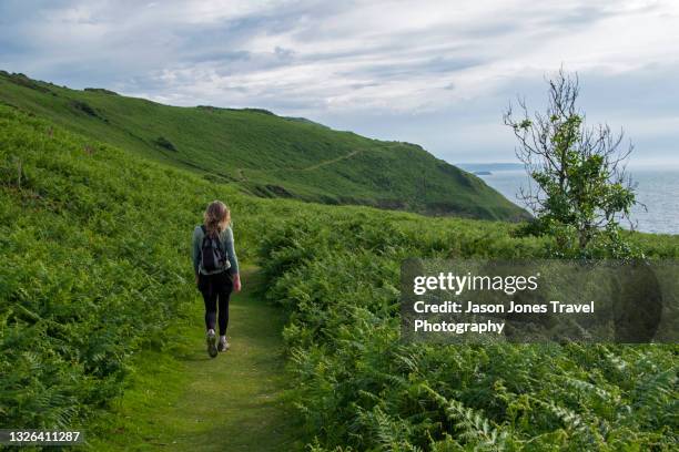 a woman on a walking trail in cwmtydu on the pembroke coast - ceredigion stockfoto's en -beelden
