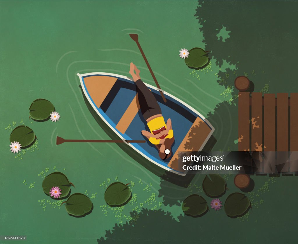 View from above woman relaxing in boat on lily pond