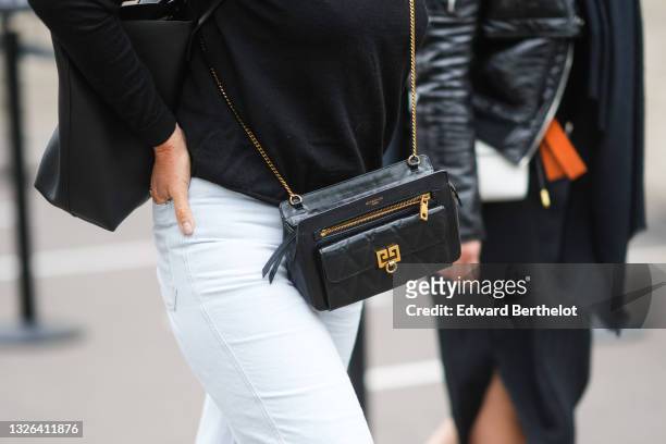 Guest wears a black t-shirt, white denim jeans pants, a black shiny leather crossbody bag from Givenchy, outside Arigato party, during Paris Fashion...