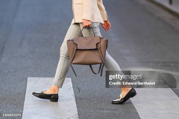 Guest wears a beige blazer jacket, gray pale denim jeans pants, black shiny leather and white loafers / shoes, a brown shiny leather Celine handbag,...