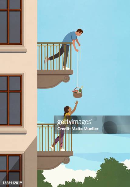 man lowering gift basket to woman below on apartment balcony - lowering stock illustrations